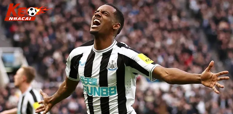 Isak tranh bóng trong màu áo Newcastle, phía xa là cầu thủ Liverpool